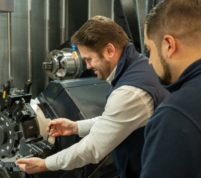 NCMT trainer providing hands-on CNC machine tool training at turning centre with customer engineer.