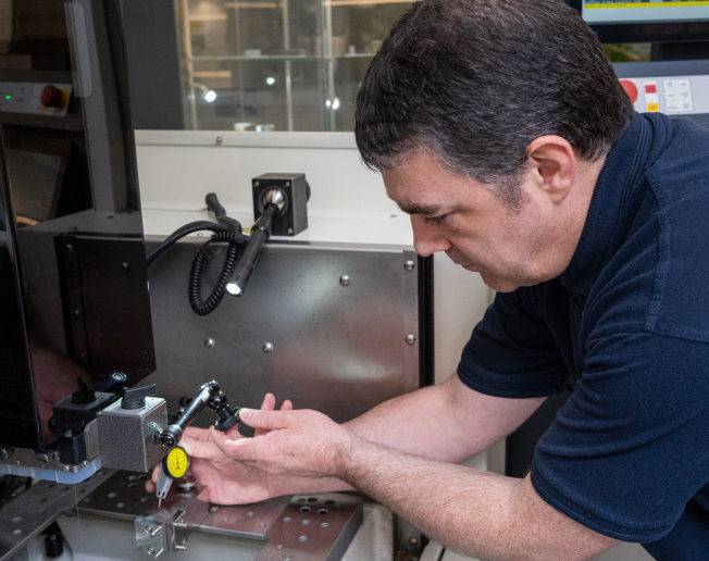 NCMT engineer calibrating precision component inside CNC machine as part of preventative maintenance service.