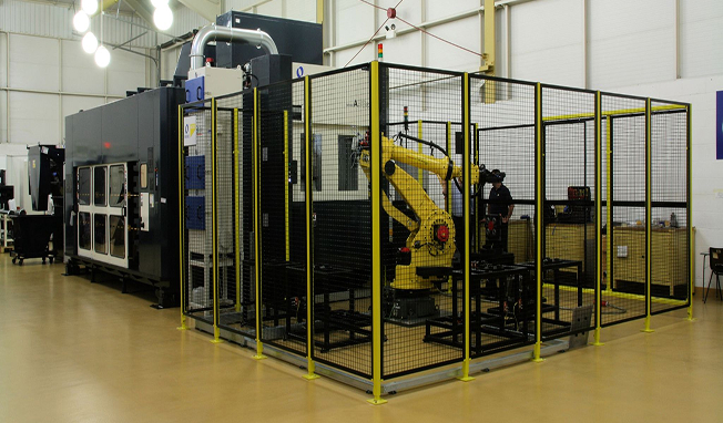 AUT-4 Large automated CNC Makino machining cell with industrial robot operating inside a safety enclosure for high-volume manufacturing.