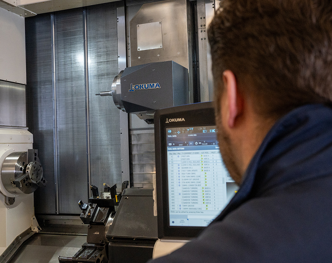 NCMT service engineer operating Okuma CNC machine tool during on-site service and maintenance support.