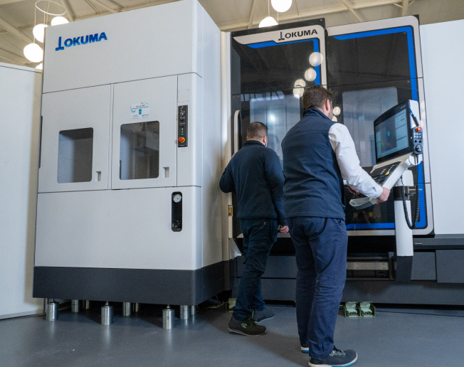 NCMT engineers carrying out machine tool service and operational checks on Okuma machining centre in UK facility.
