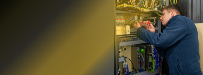 NCMT engineer servicing an electrical control cabinet, checking wiring and components.