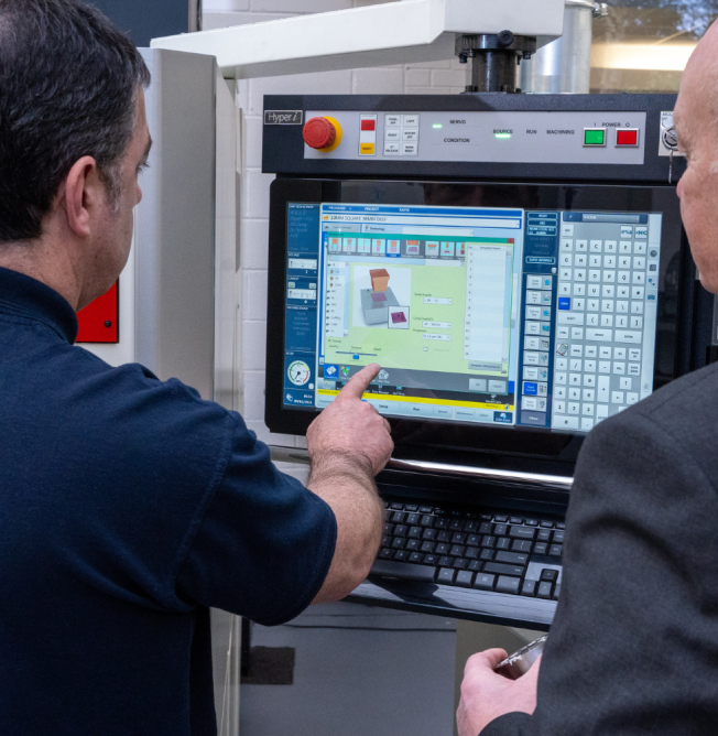 trunky Engineer demonstrating CNC machining programme on a machine control interface during technical setup.