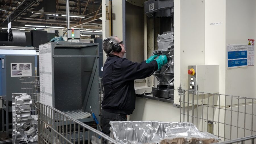 CNC operator loading aluminium EV housing into Makino horizontal machining centre, precision machining of electric vehicle components in UK automotive manufacturing facility