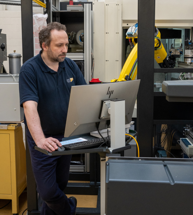 NCMT automation engineer programming robotic machining cell using industrial control workstation in Coventry Technology Centre.
