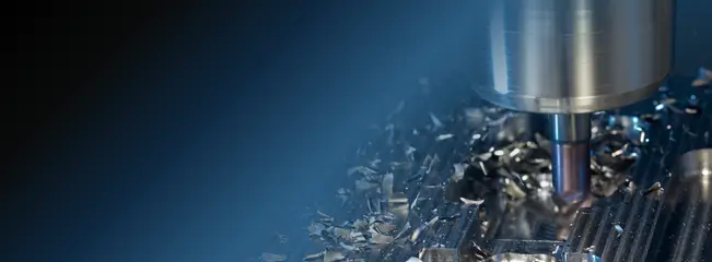 CNC milling cutter machining a metal component, with swarf visible around the tool.